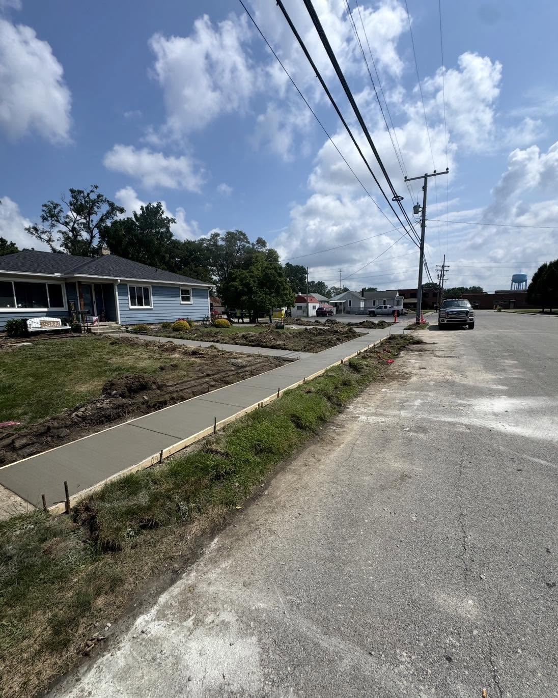 New street-side concrete sidewalk alongside a driveway